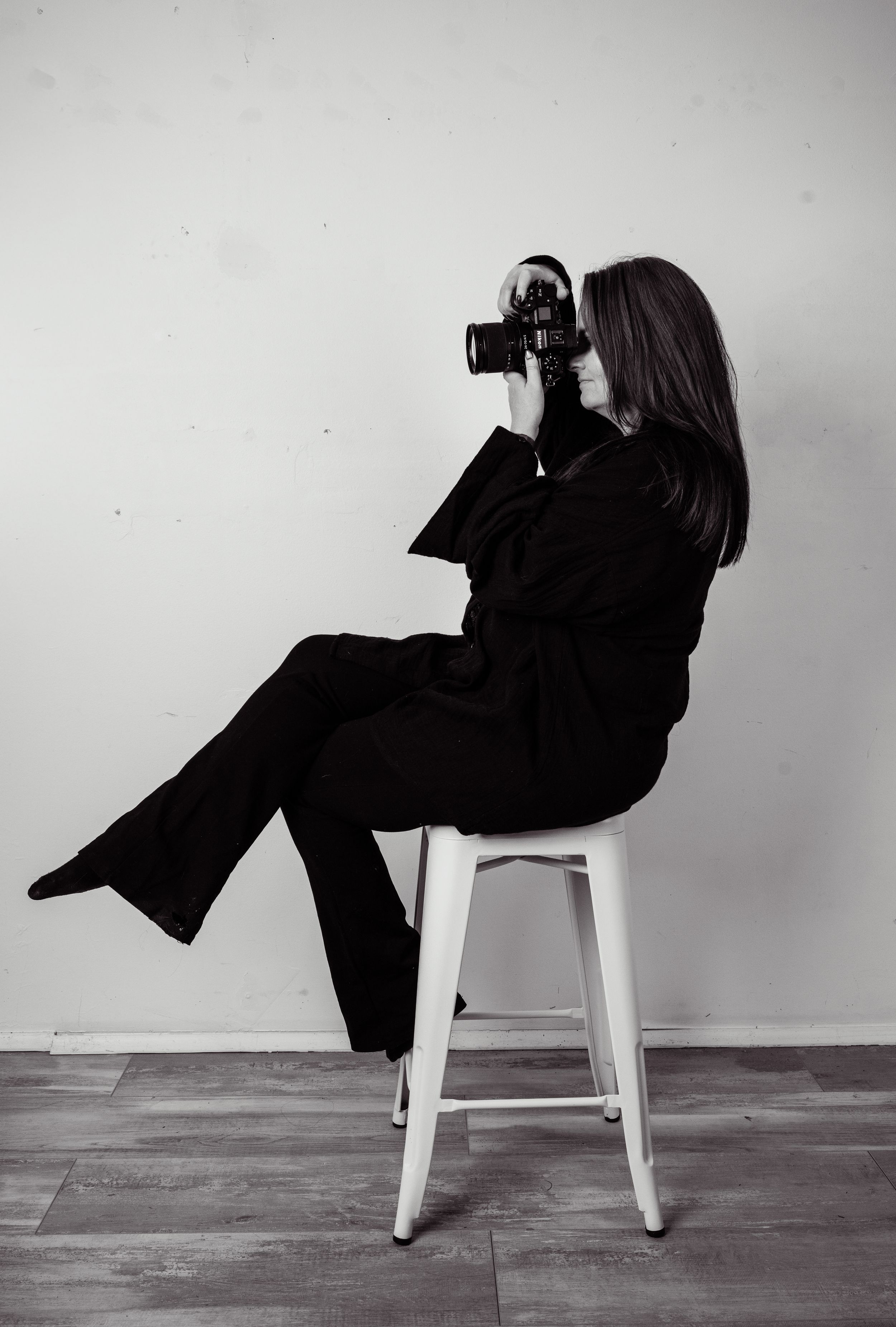 Fashion photoshoot featuring emerald green lace outfit and black boots against white studio backdrop.