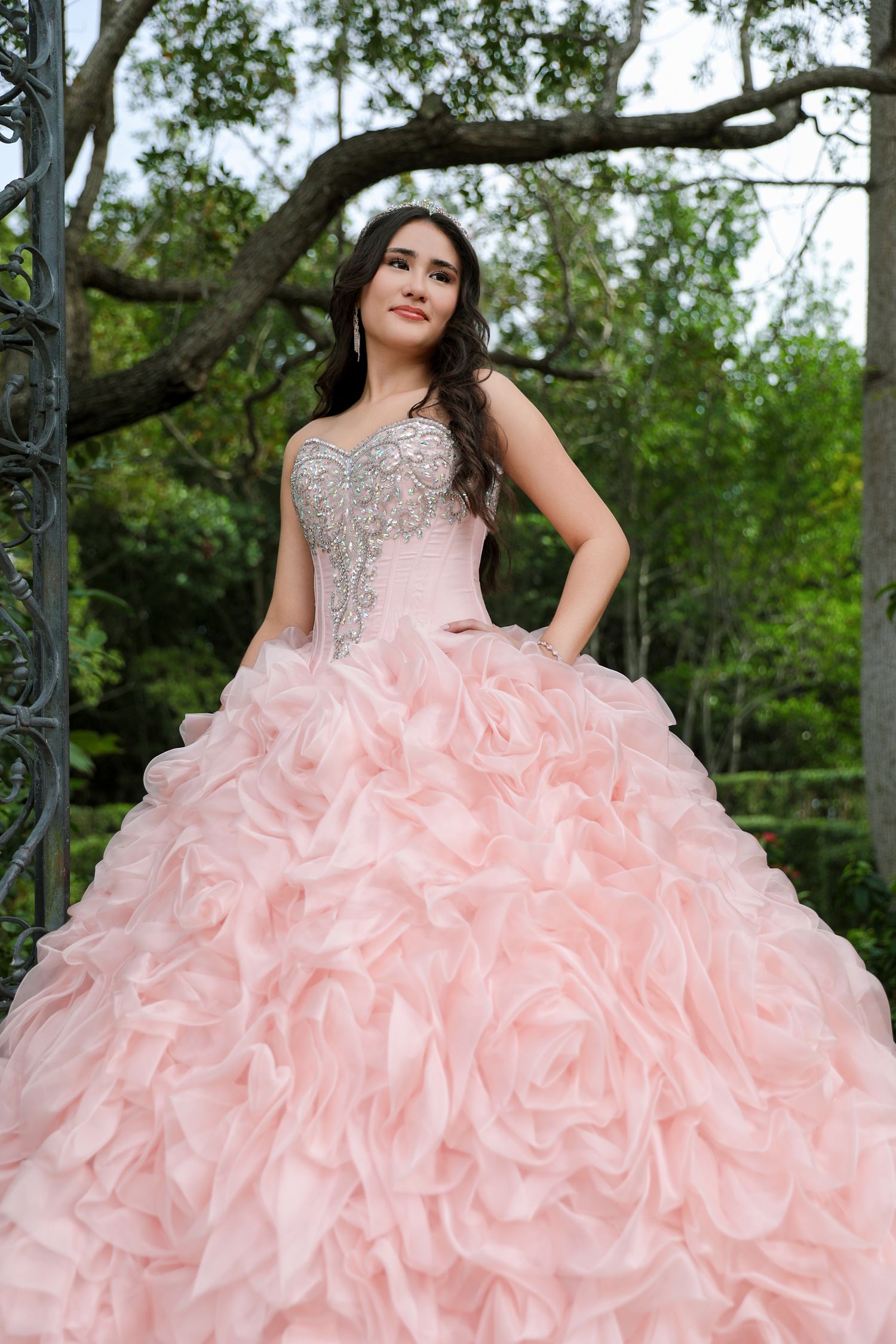Pink ruffled ballgown with beaded bodice photographed in garden setting.