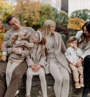 Casual family portrait showing playful interaction while sitting on stone wall outdoors.