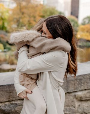 Intimate embrace between parent and child both wearing cream colored winter coats.