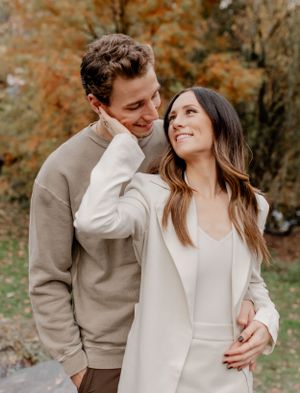 Couple in neutral sweaters sharing intimate moment in autumn park setting.