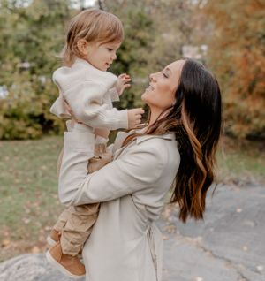 A tender moment between parent and child wearing matching cream-colored outfits in an autumn setting.