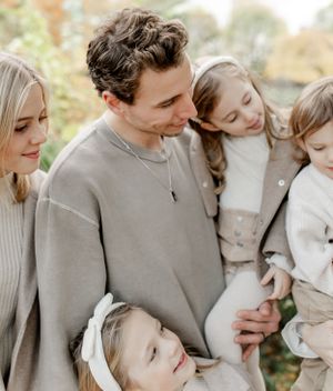 Family dressed in coordinating neutral tones sharing an intimate moment outdoors.