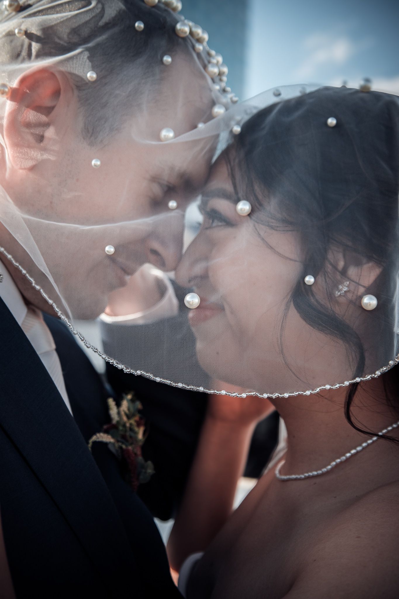 Bride and groom smiling at each other under the bride's veil