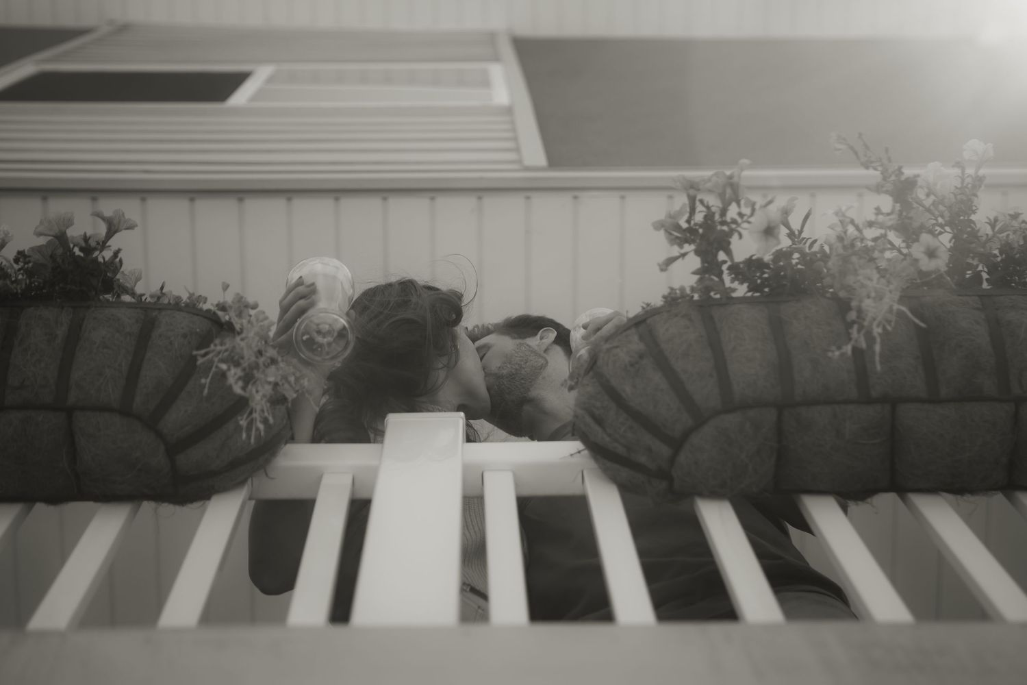 Black and white close-up of hands playing piano keys with decorative planters.