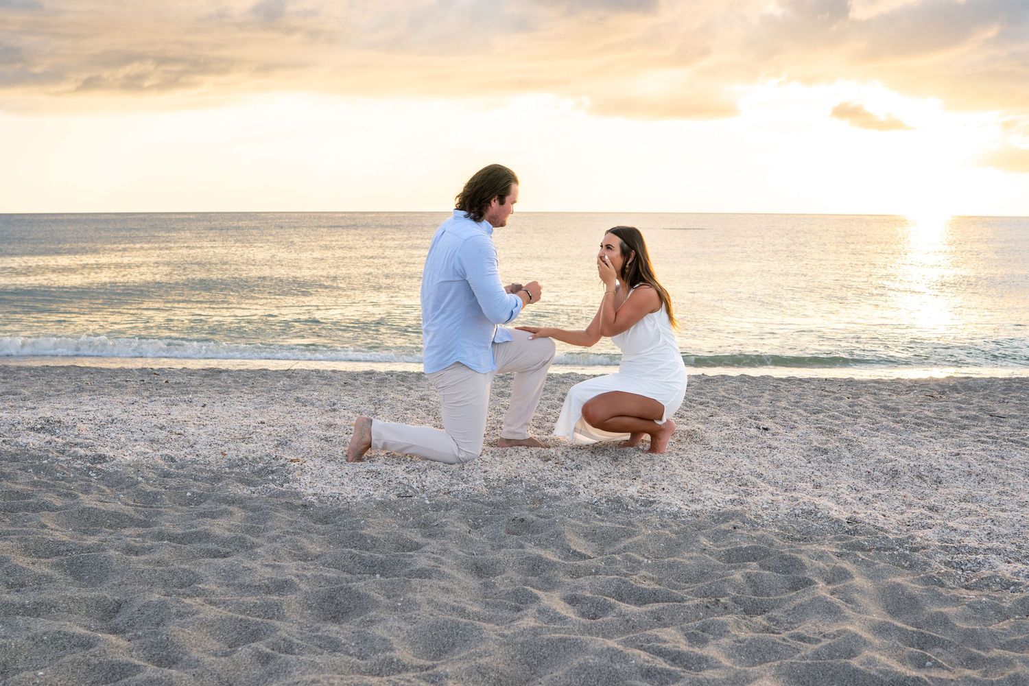 Couple sharing romantic moment during beach marriage proposal at sunset.