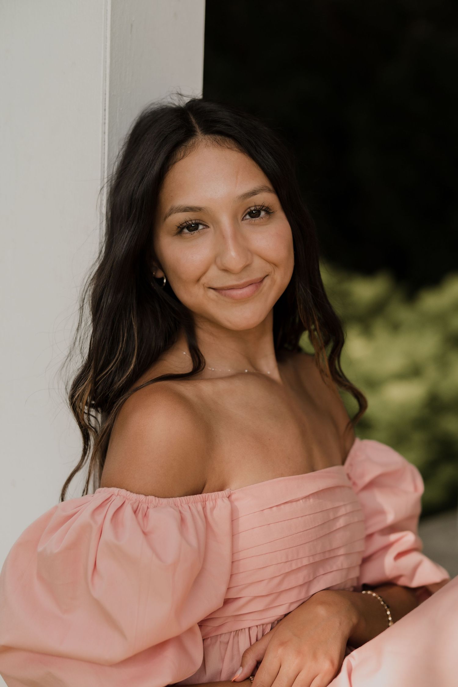 A soft pink off-shoulder top photographed in a natural outdoor setting.