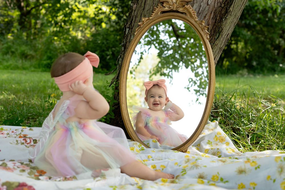 A sunny outdoor photoshoot setup featuring an antique gold mirror against a tree.