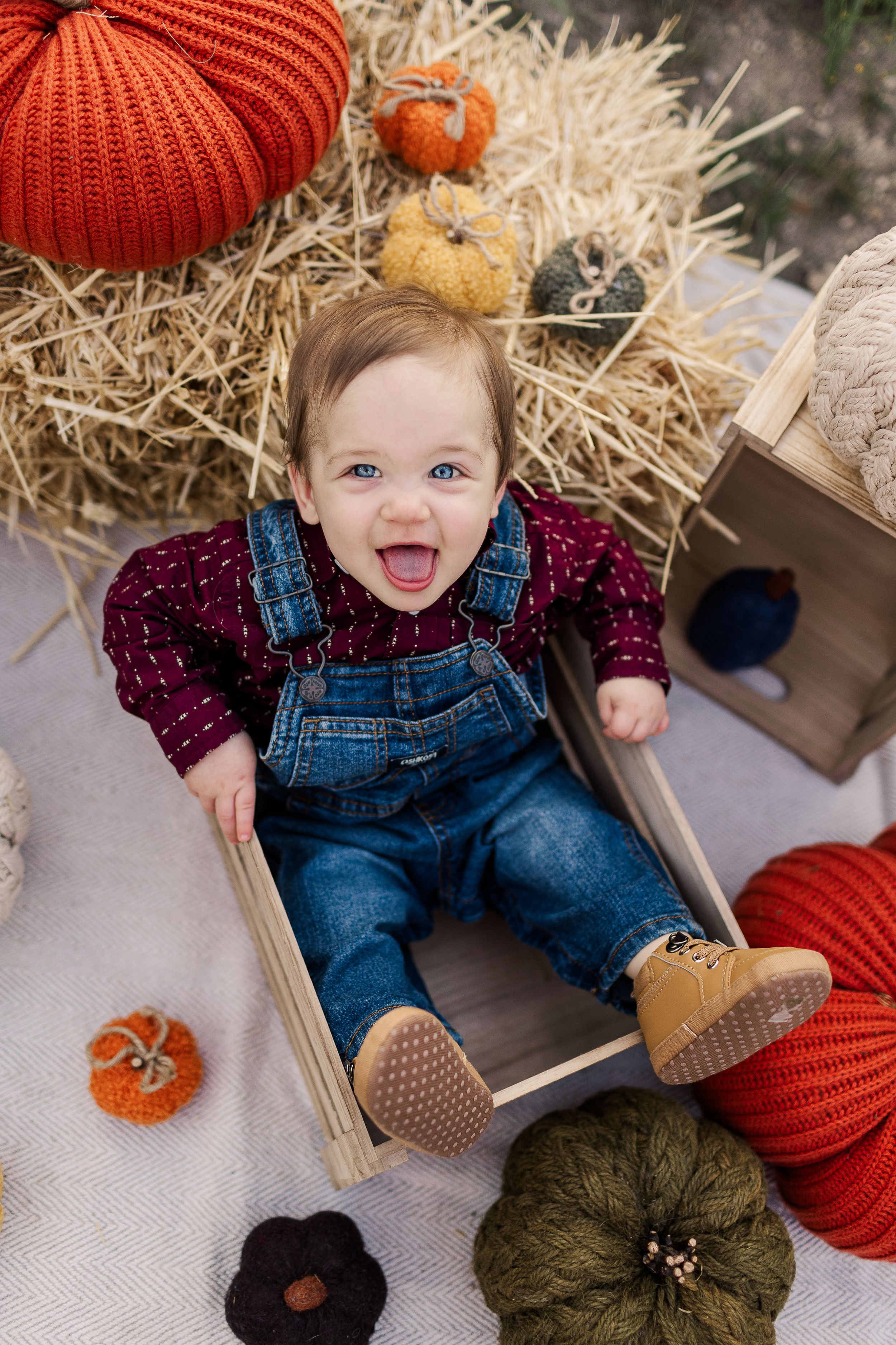 Festive fall photo setup with knit pumpkins and wooden crate creates cozy autumn scene.
