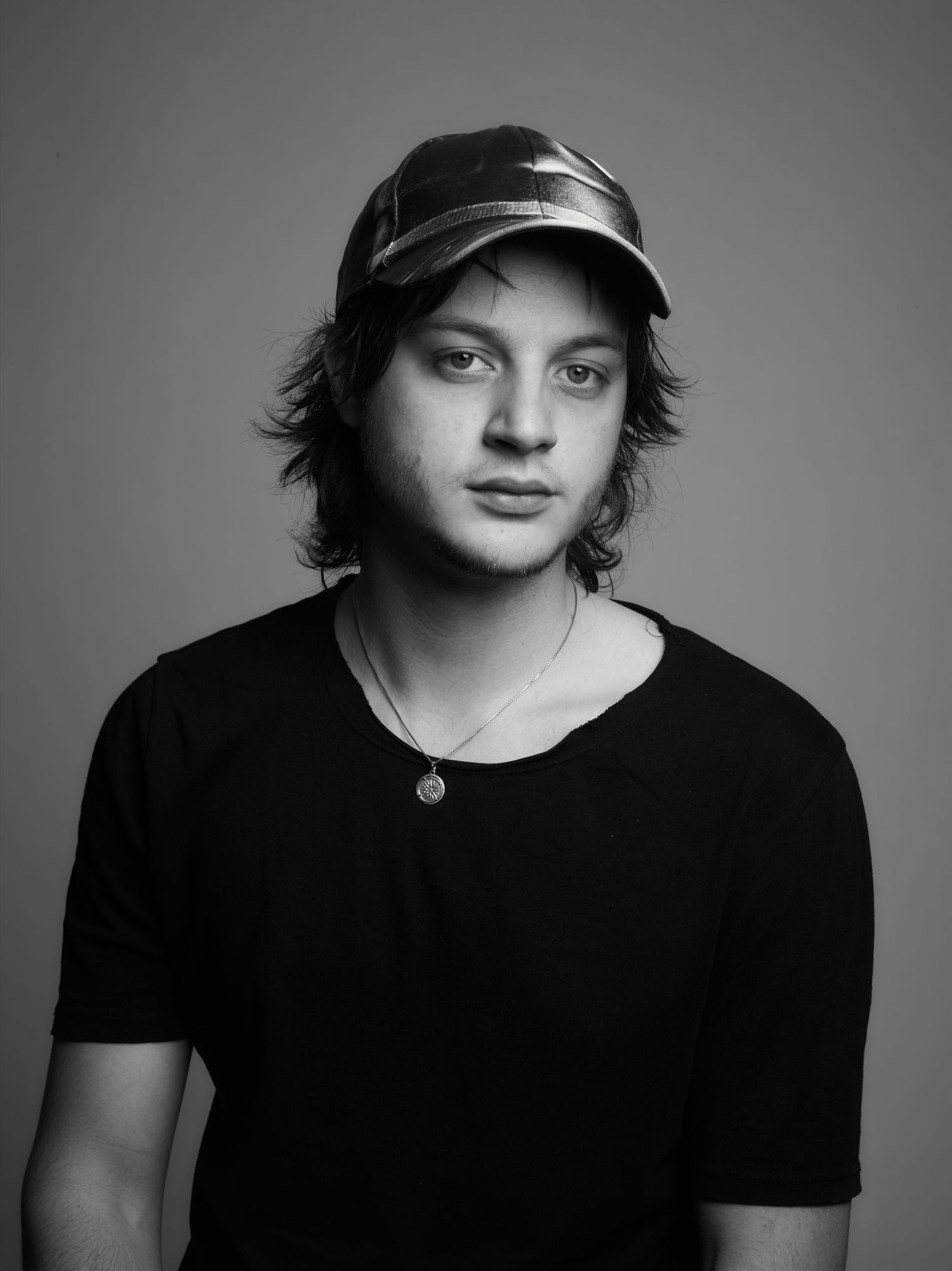 Black and white studio portrait series showing a person wearing casual attire and cap.