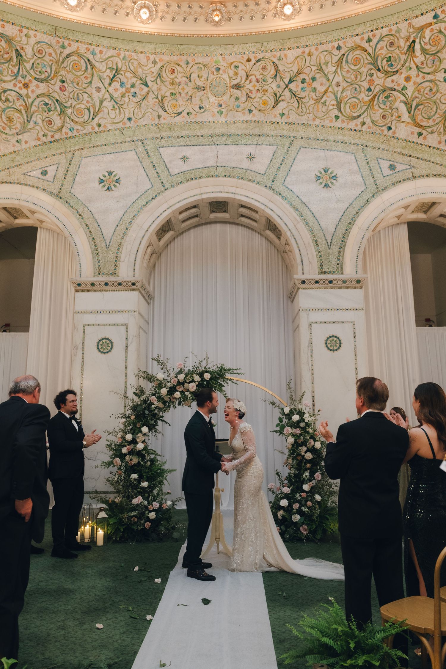 A wedding couple embracing under a garden pergola during golden hour.