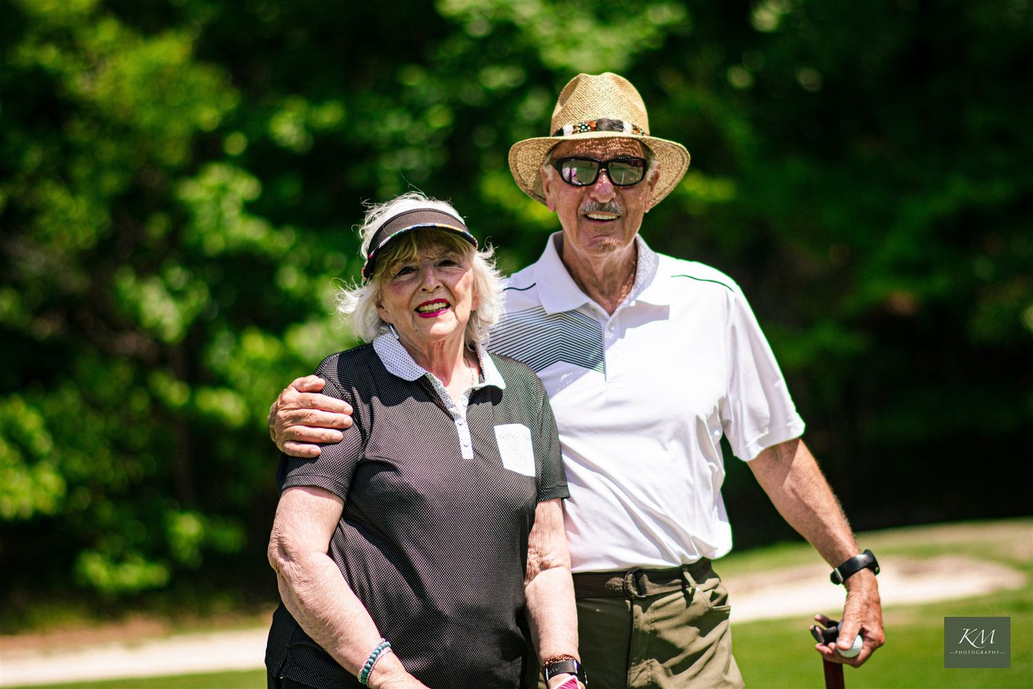 A man and a women smiling outside with golf clubs, Birmingham Alabama corporate event photographer.