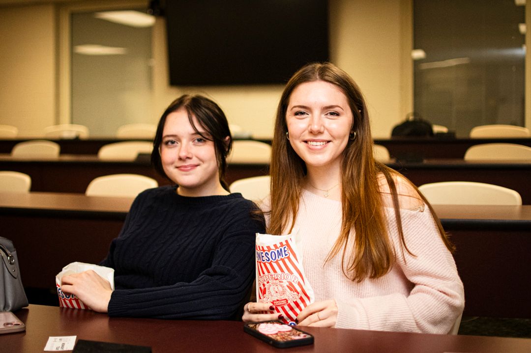 Two women smiling holding bags of popcorn, Jefferson State Community College event photography, Professional event photographer.