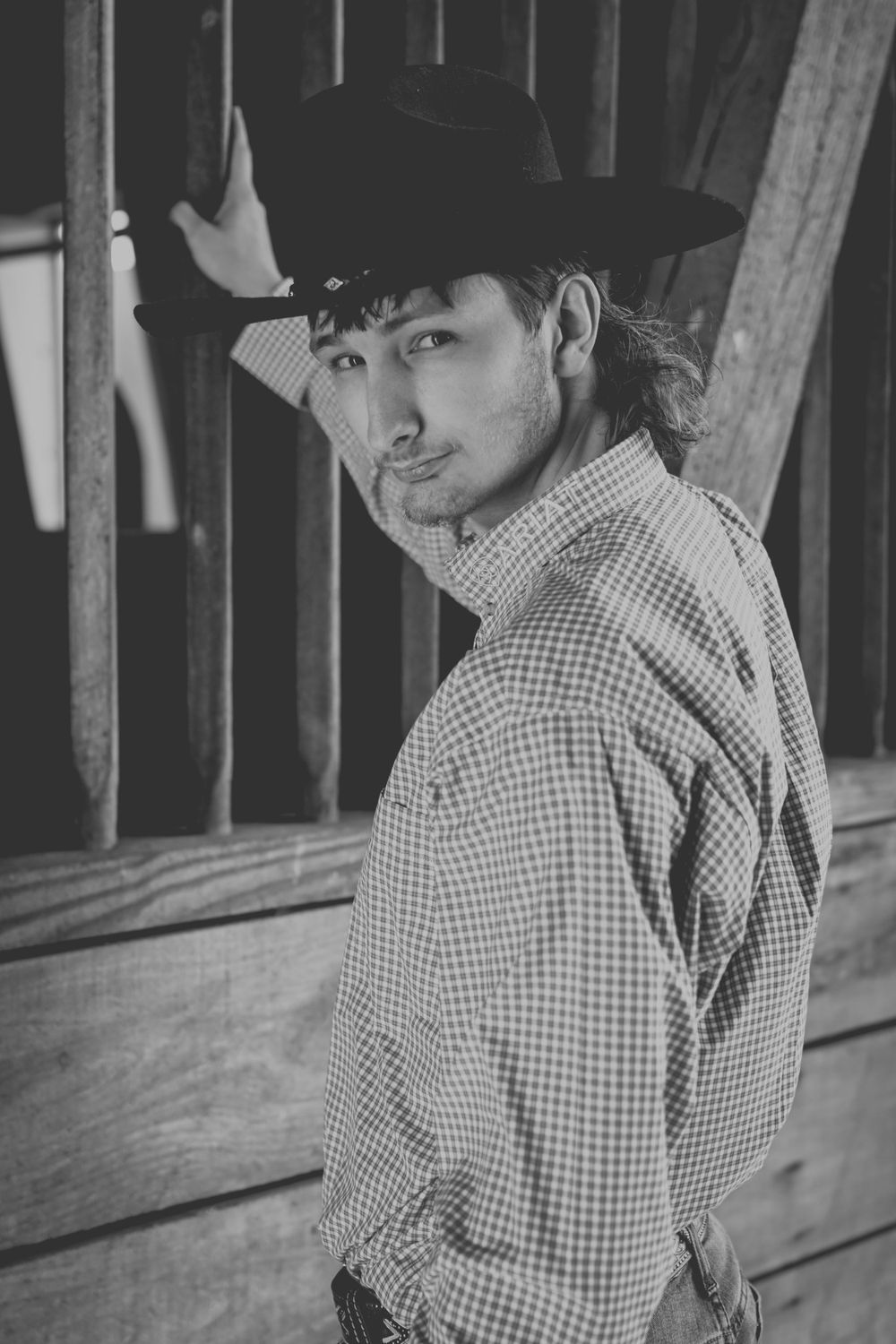 Senior boy looks back at photographer in barn.