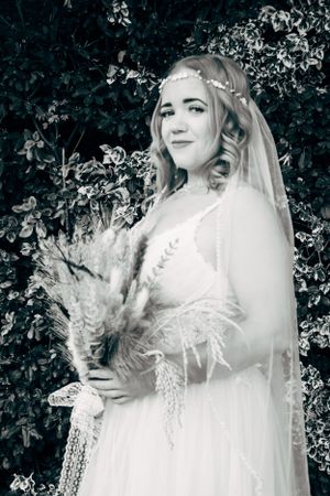 A dreamy bridal portrait with the bride holding dried flowers while wearing a delicate veil and crown.