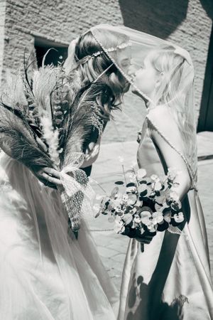 A close-up black and white photo of a bridal bouquet with feathers and flowers.