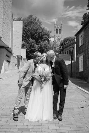 A candid wedding moment captured in black and white with a church spire in the distance.