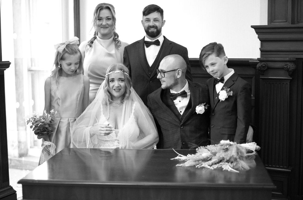 Wedding party gathered around a table during document signing at a formal ceremony.