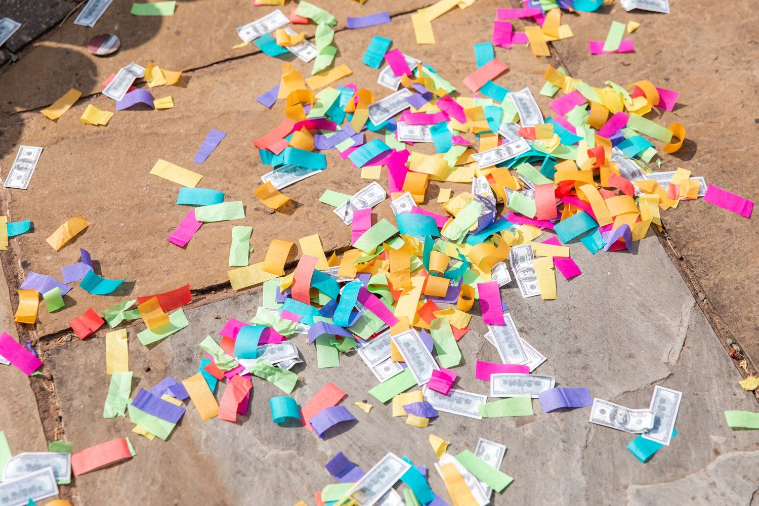 Colorful confetti and ticket stubs scattered on a concrete ground after a festive celebration or event.