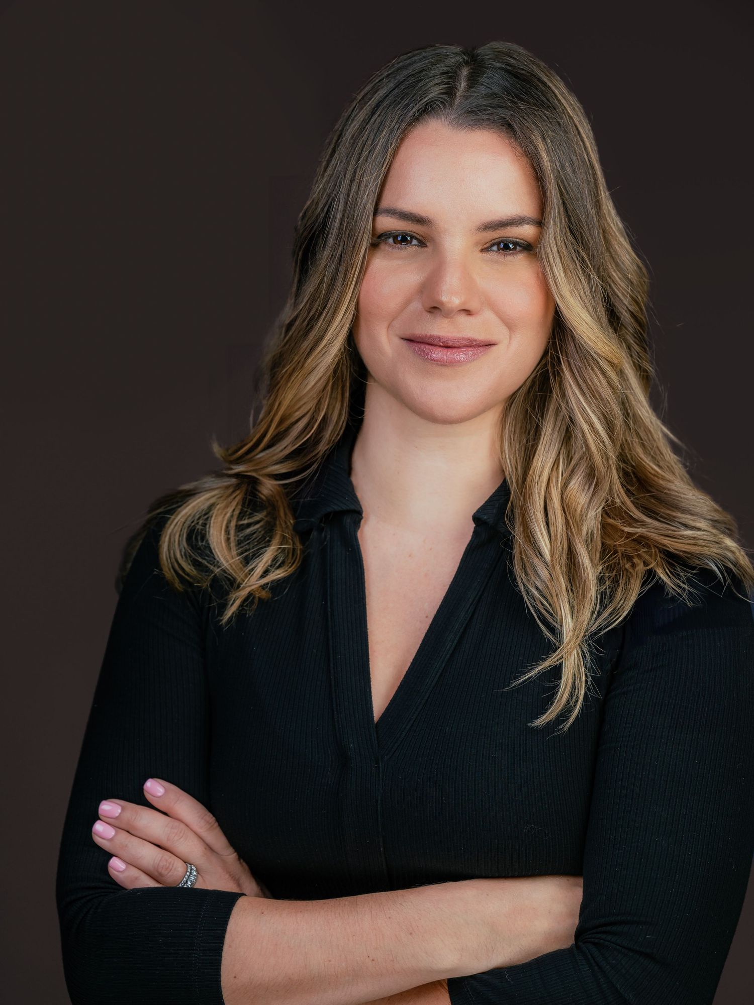 Professional studio portrait of someone wearing a cream colored sweater against a white background.