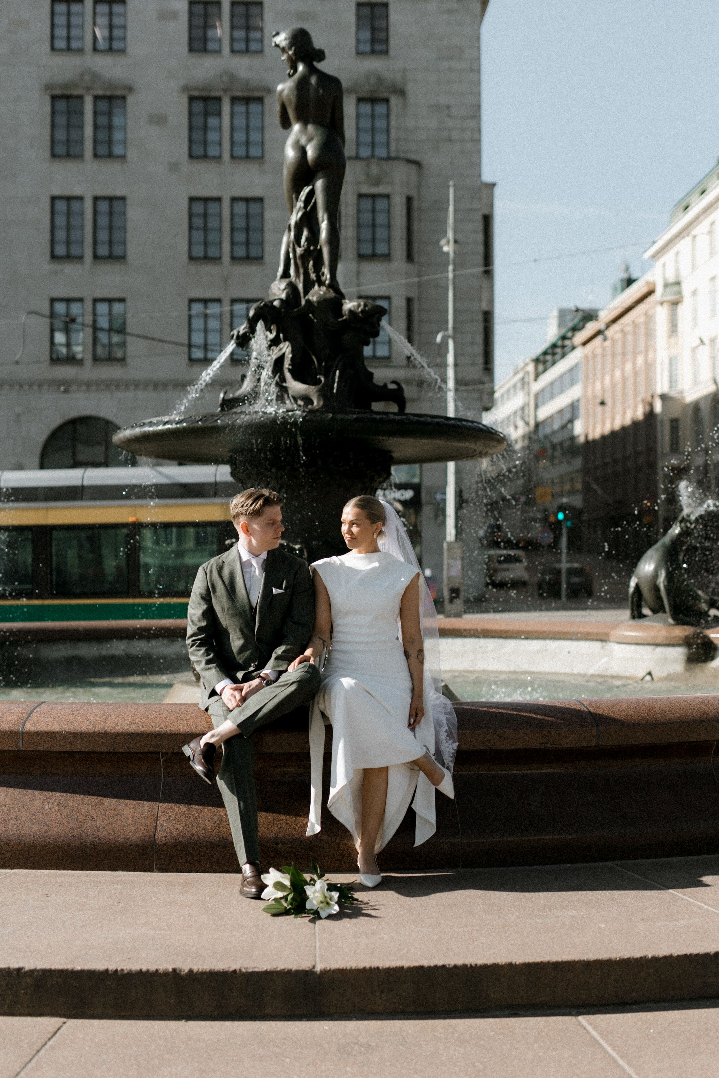 Wedding couple sits on the Havis Amanda fountain in Helsinki, Finland. Photo by wedding photographer Anita Vartiainen.
