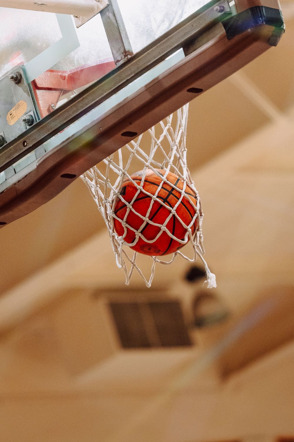 A basketball swishes through a white net in a sequence of four progressive shots showing the ball's downward motion.