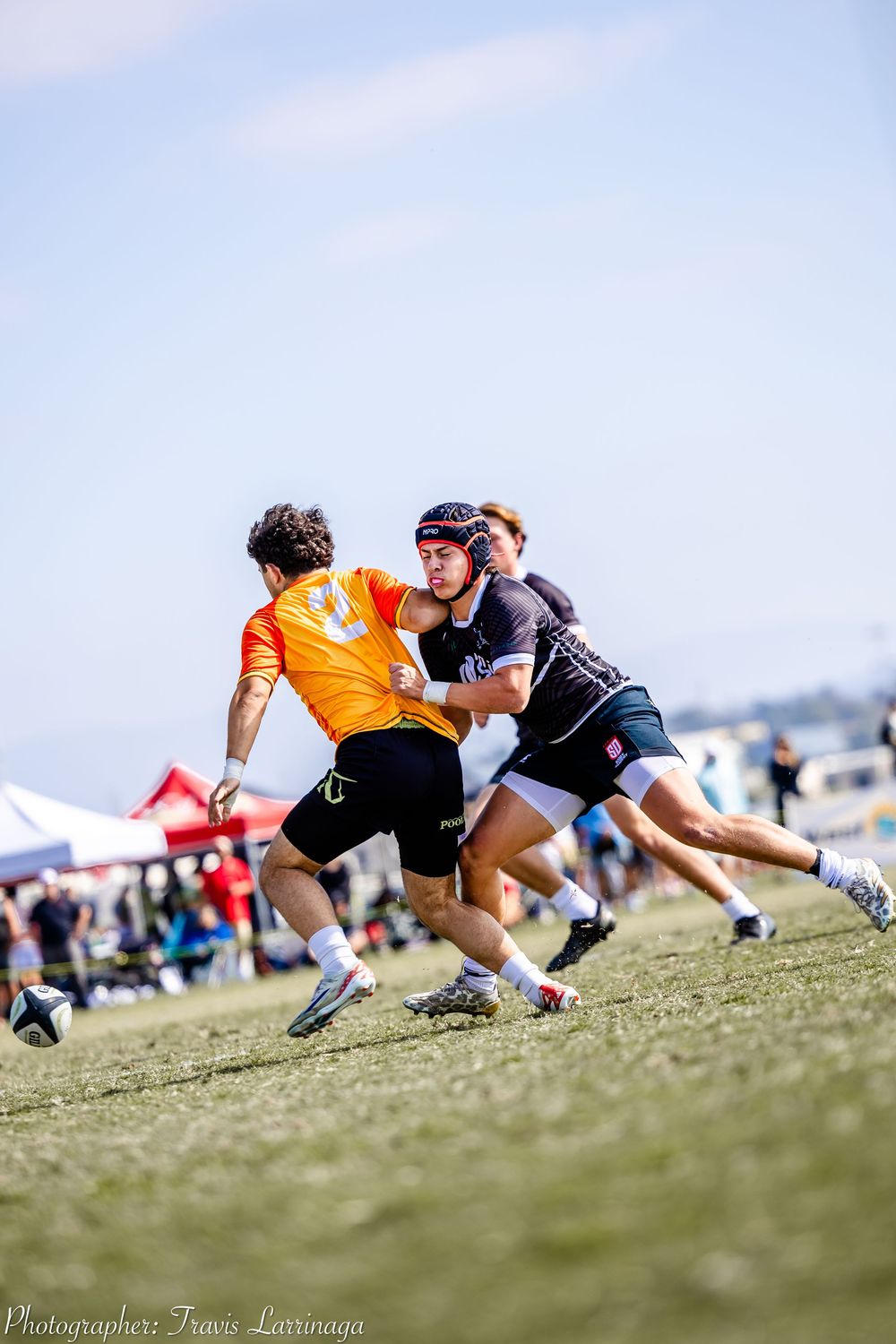 Rugby players diving and tackling on a grassy field during a match.