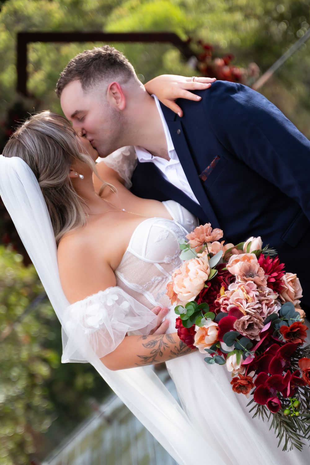 A romantic wedding scene showcasing a stunning burgundy and peach floral bouquet.