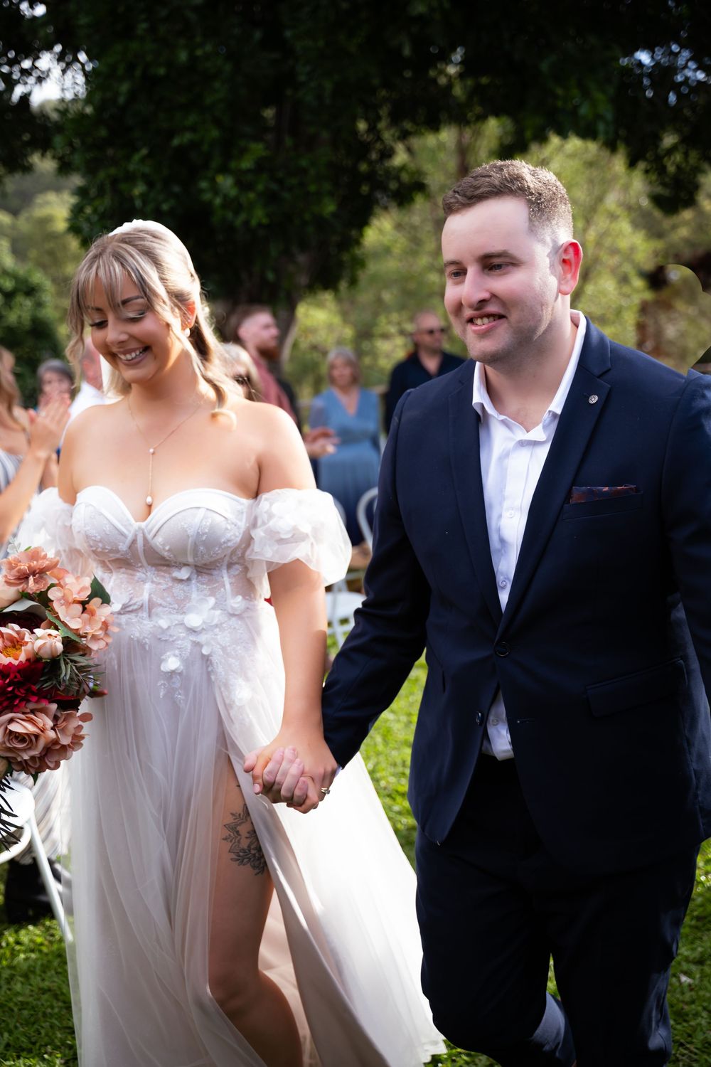 Elegant outdoor wedding scene with couple in formal attire walking together.