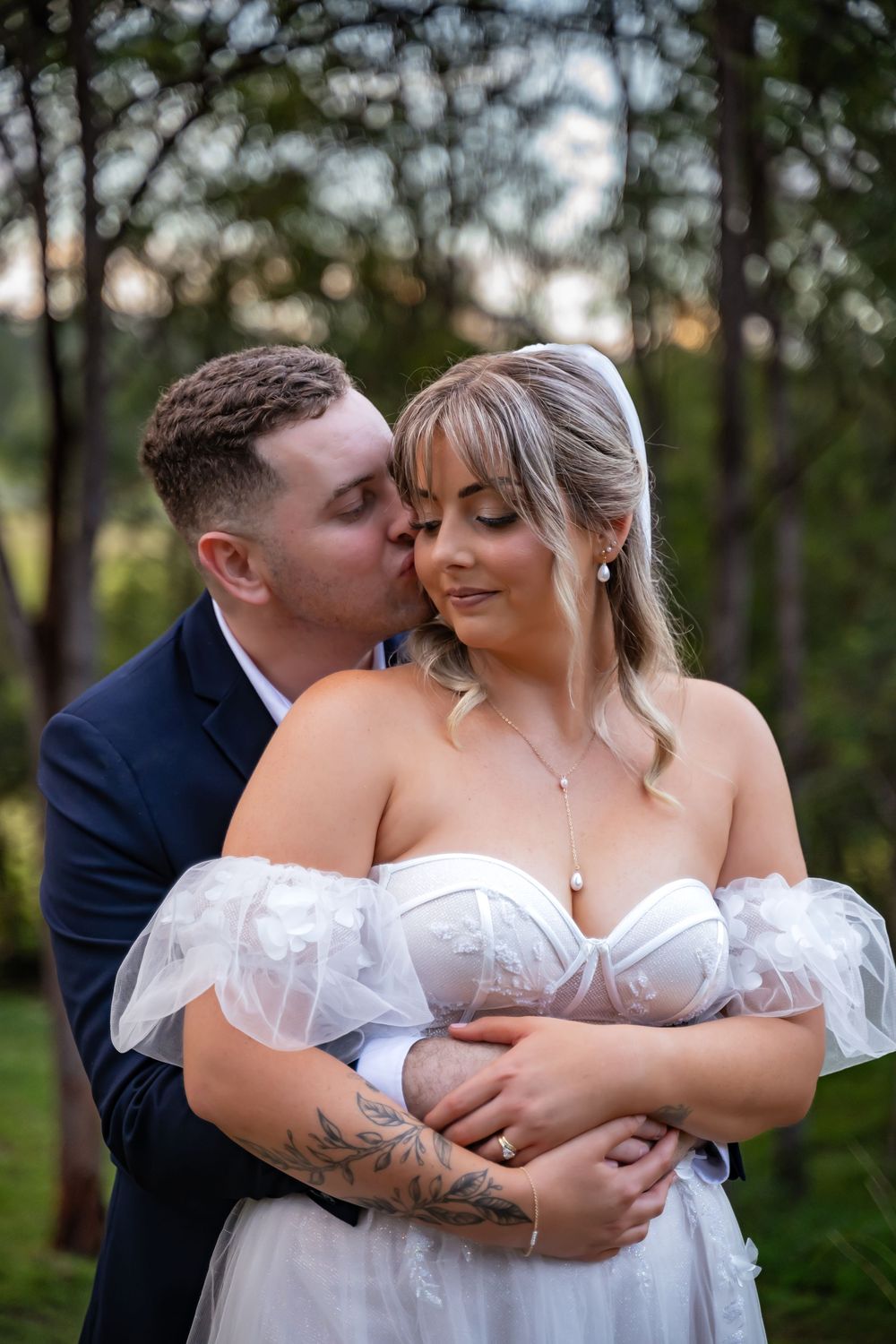 Tender embrace between newlyweds against a natural forest backdrop.