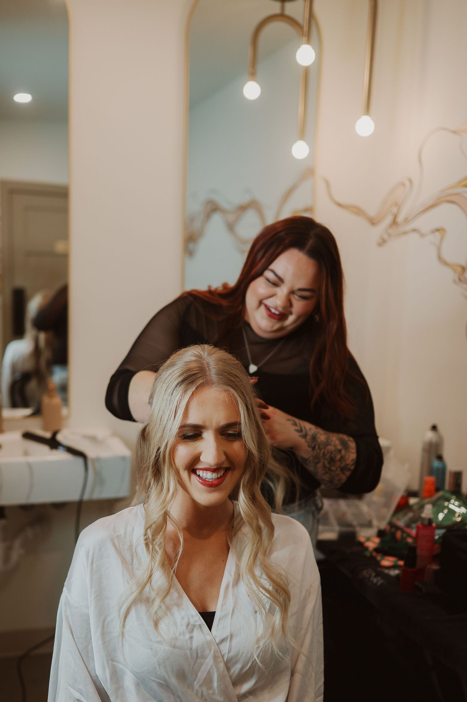 A person getting their hair styled in a salon with warm lighting and decorative wall art.