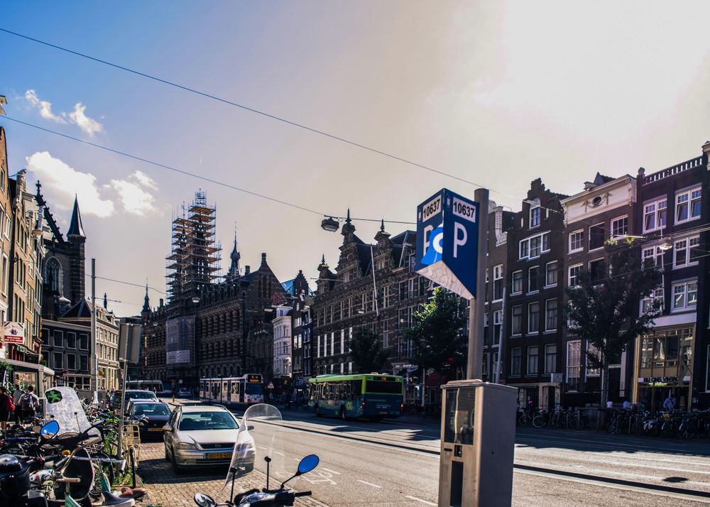 Historic street view in Amsterdam with traditional architecture and a church spire in the distance.
