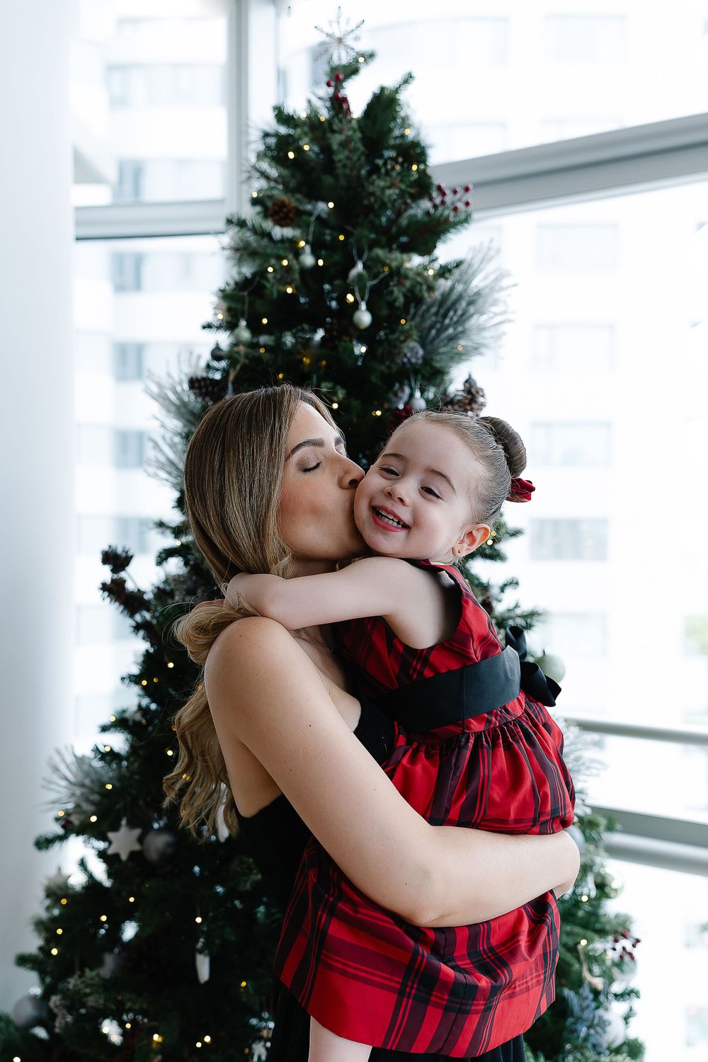A tender holiday moment shared in front of a decorated Christmas tree.