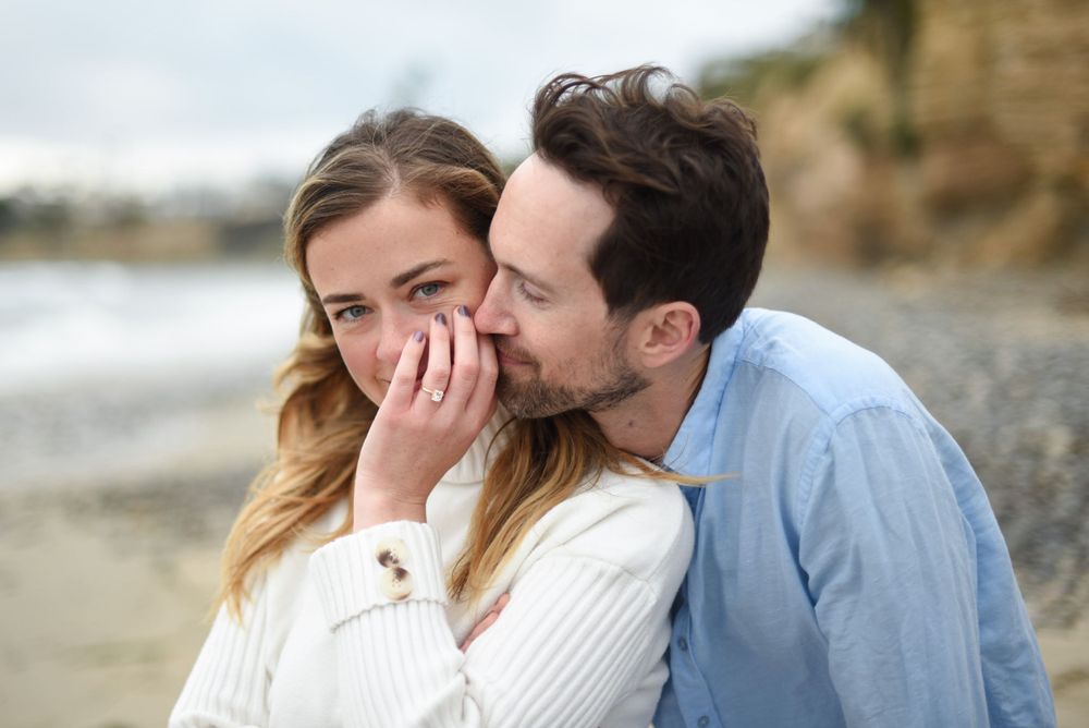 An intimate moment shared between a couple on a cloudy beach day.