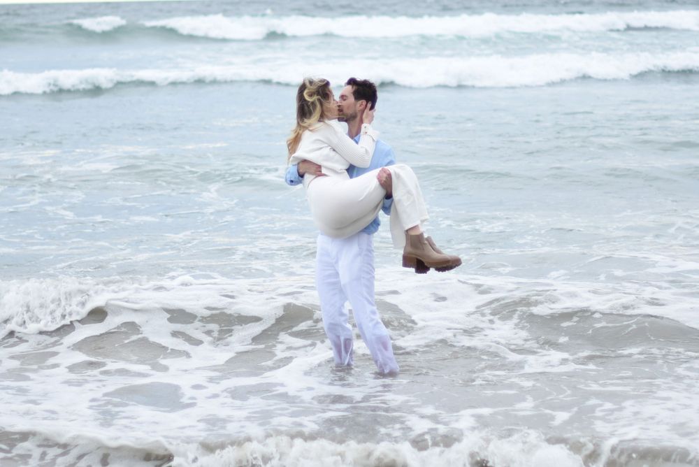 A romantic embrace on a beach with crashing waves in the background.