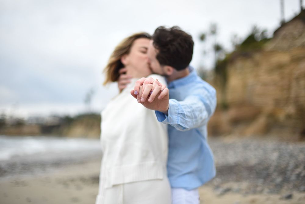A blurred motion romantic moment captured on a beach with coastal cliffs.