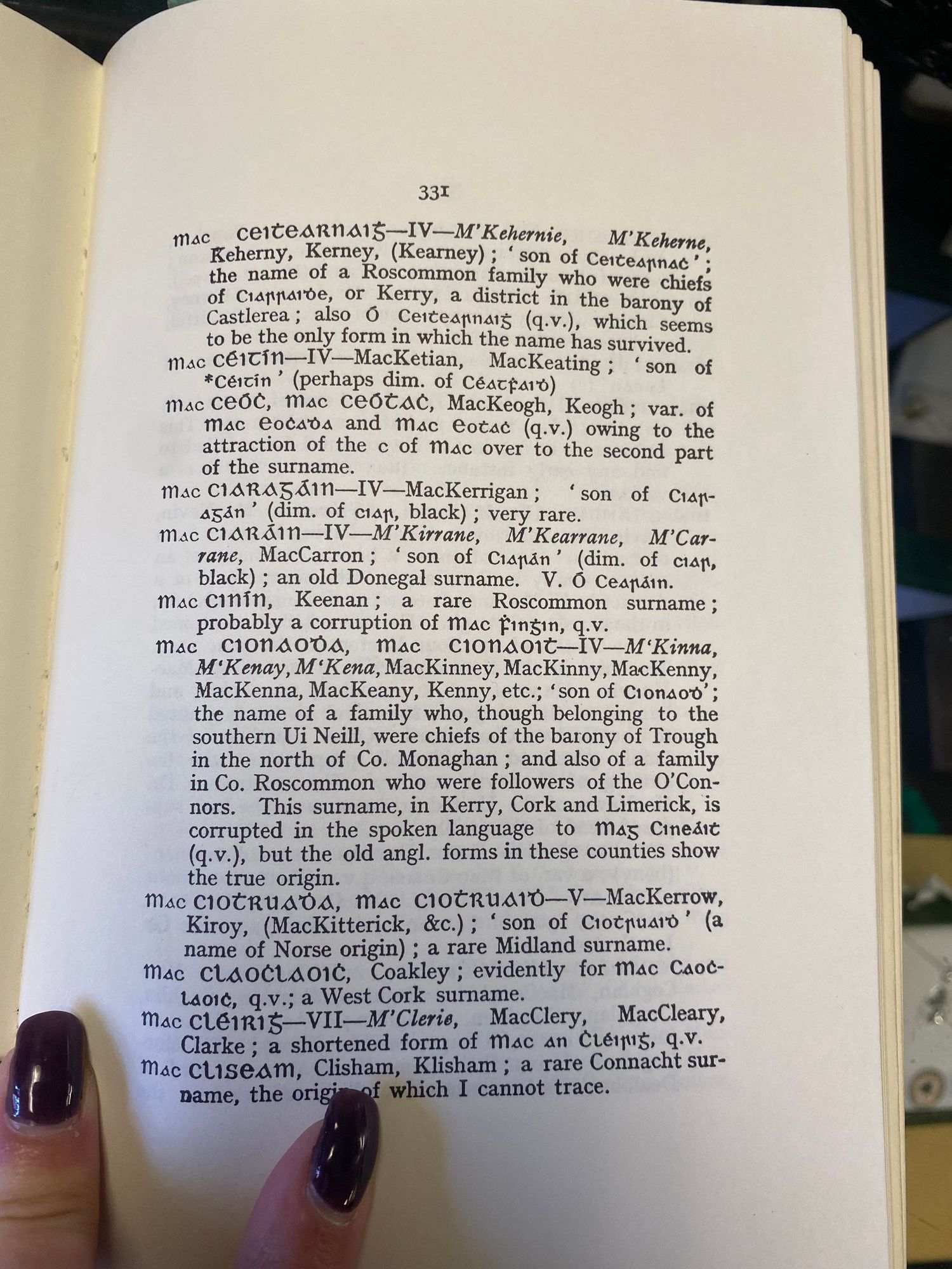 Open book page showing genealogical entries and surname origins.