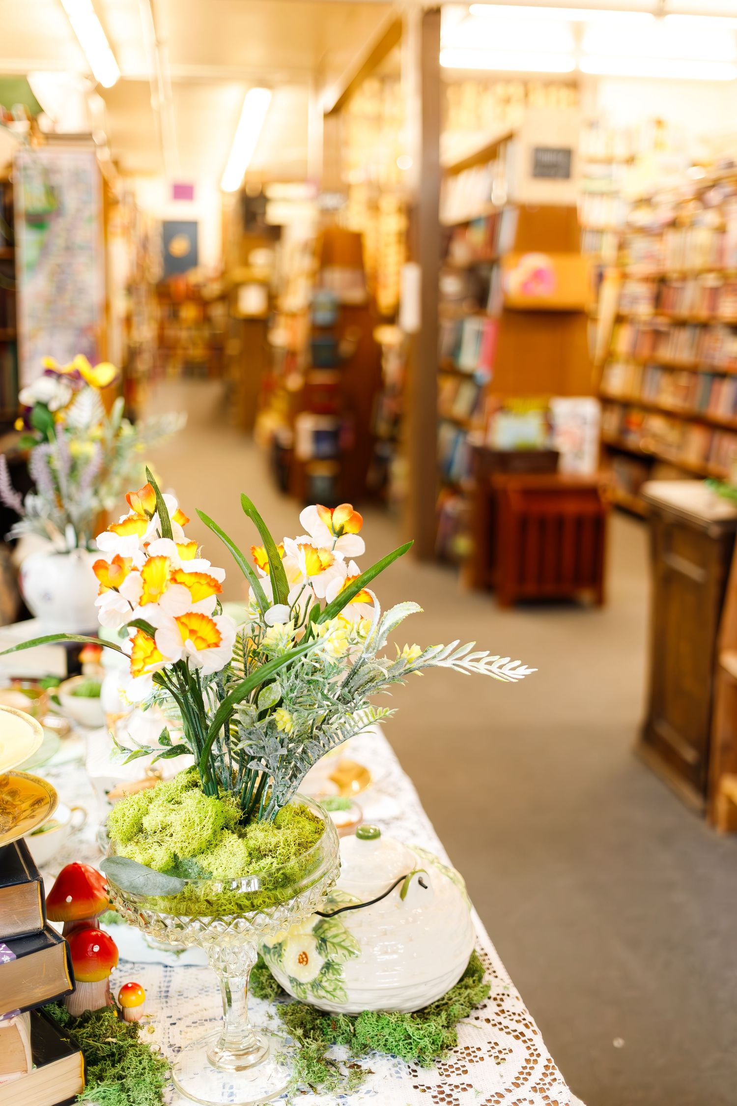 Bright yellow daffodil flower arrangement in a bookstore with bookshelves in background.