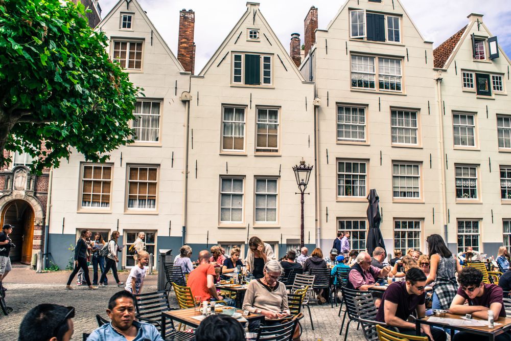Historic white buildings with traditional Dutch architecture and outdoor cafe seating.