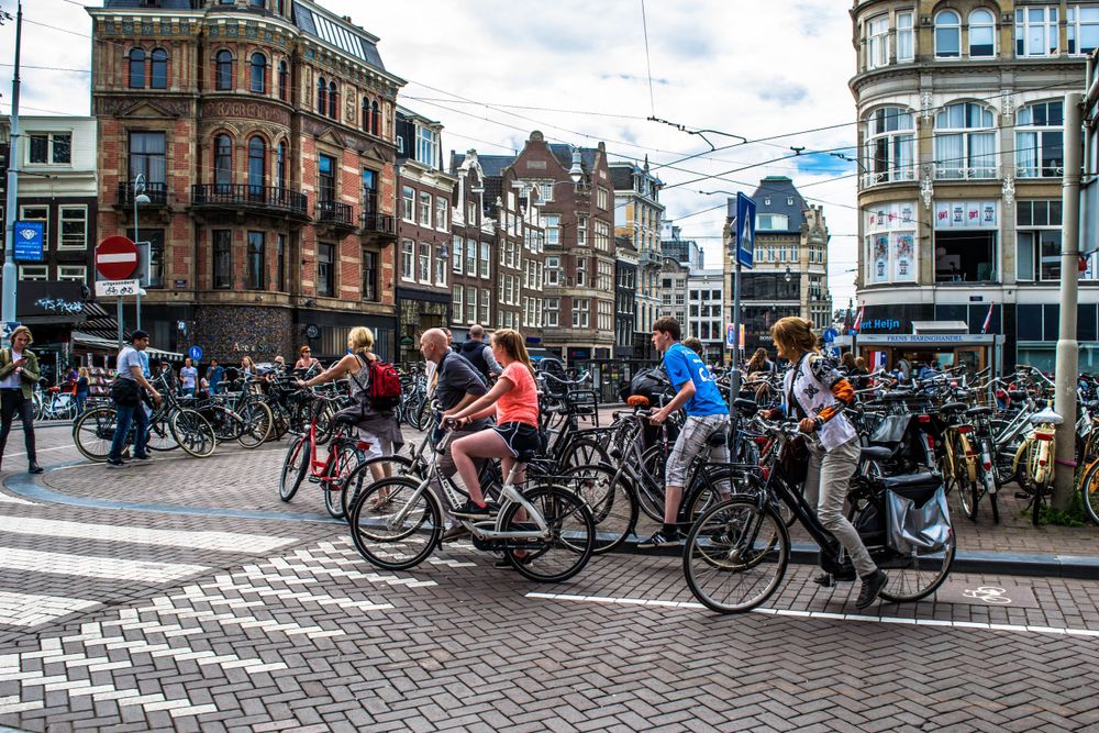 Cyclists crossing a busy intersection in Amsterdam city center.