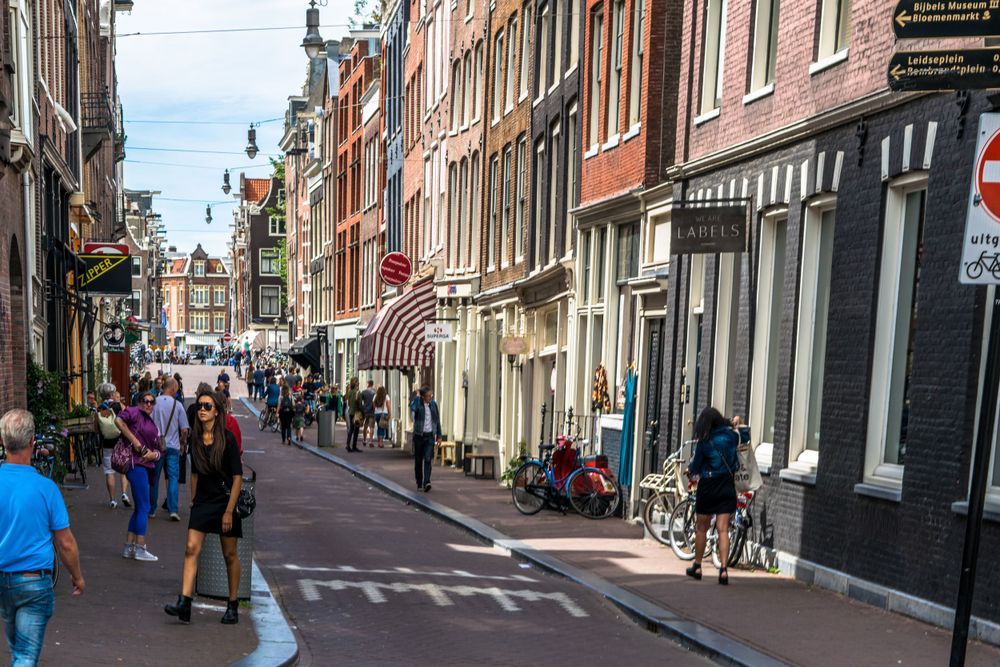 Narrow Amsterdam street lined with traditional buildings and shops.