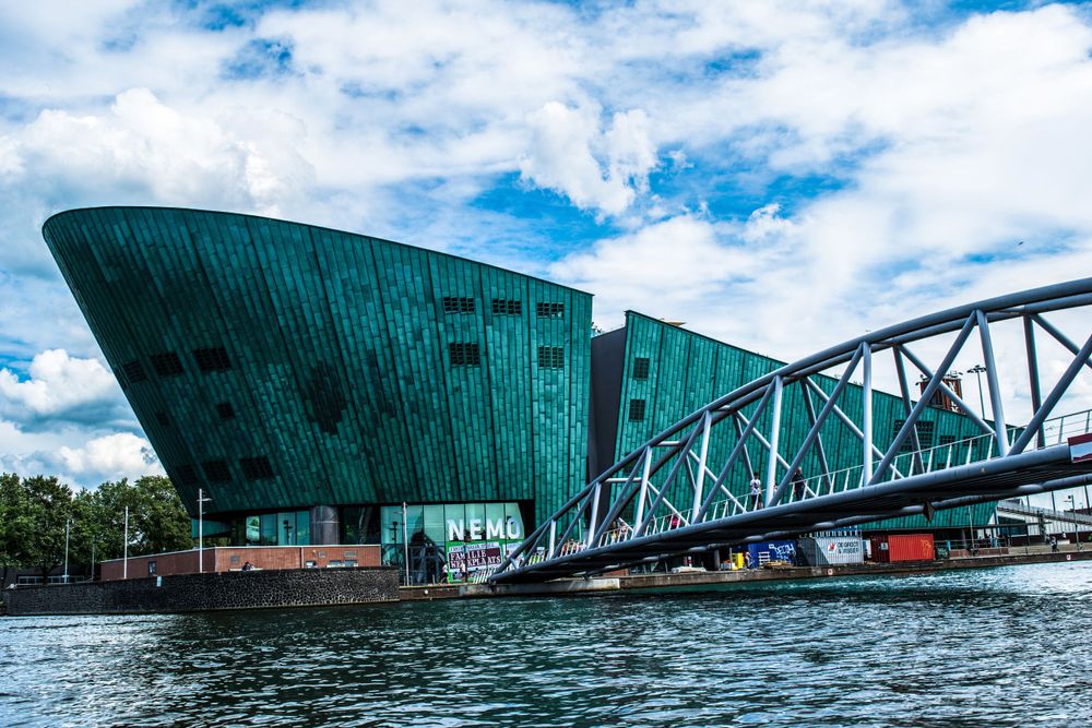 Modern green NEMO Science Museum building with distinctive architecture along Amsterdam waterfront.