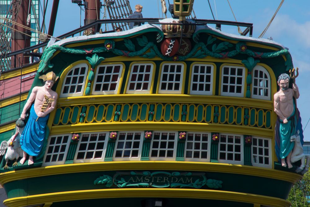 Ornate green and gold stern gallery of historic sailing vessel with detailed window panels.