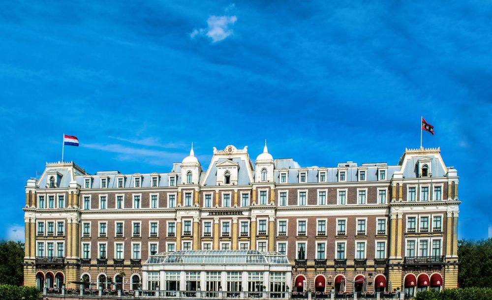 Grand Victorian-style hotel building with red brick facade and white trim against blue sky.