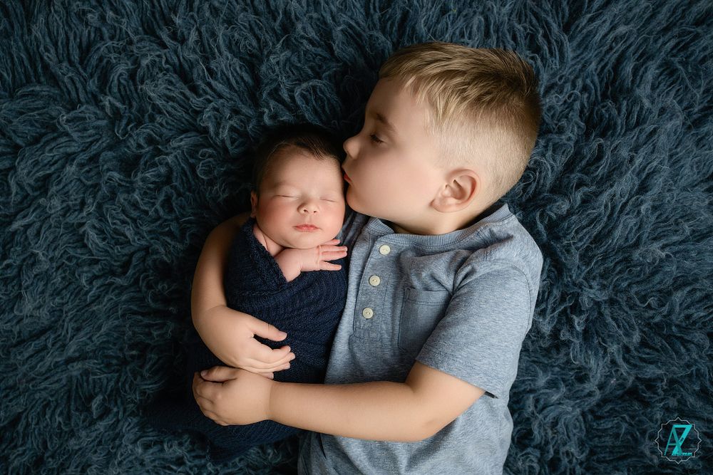 Touching sibling portrait with a tender embrace on soft gray fur background.