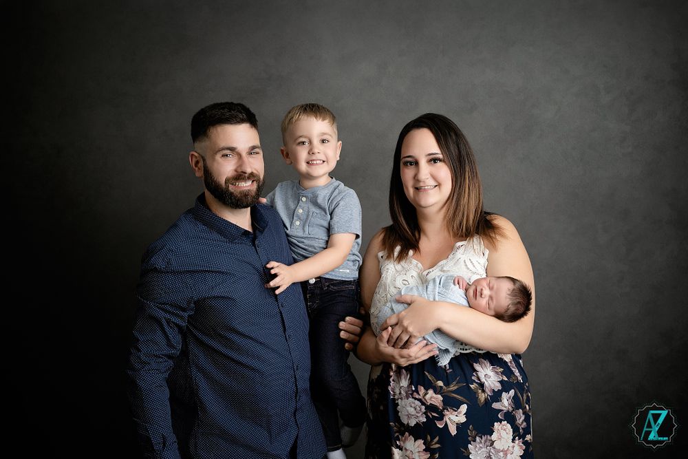 Family portrait against dark background showing parents with their two children.