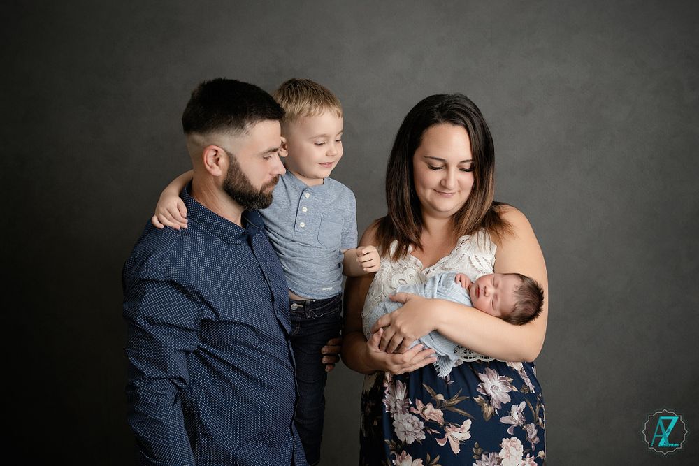 Intimate family moment captured against dark gray backdrop.