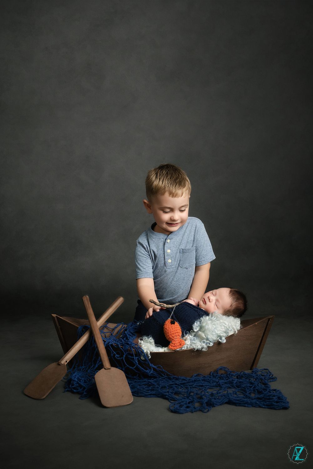 Children playing in wooden boat prop with nautical themed photography setup.