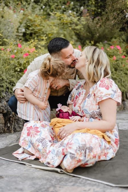 A family sharing an intimate moment together on a blanket in a blooming garden.