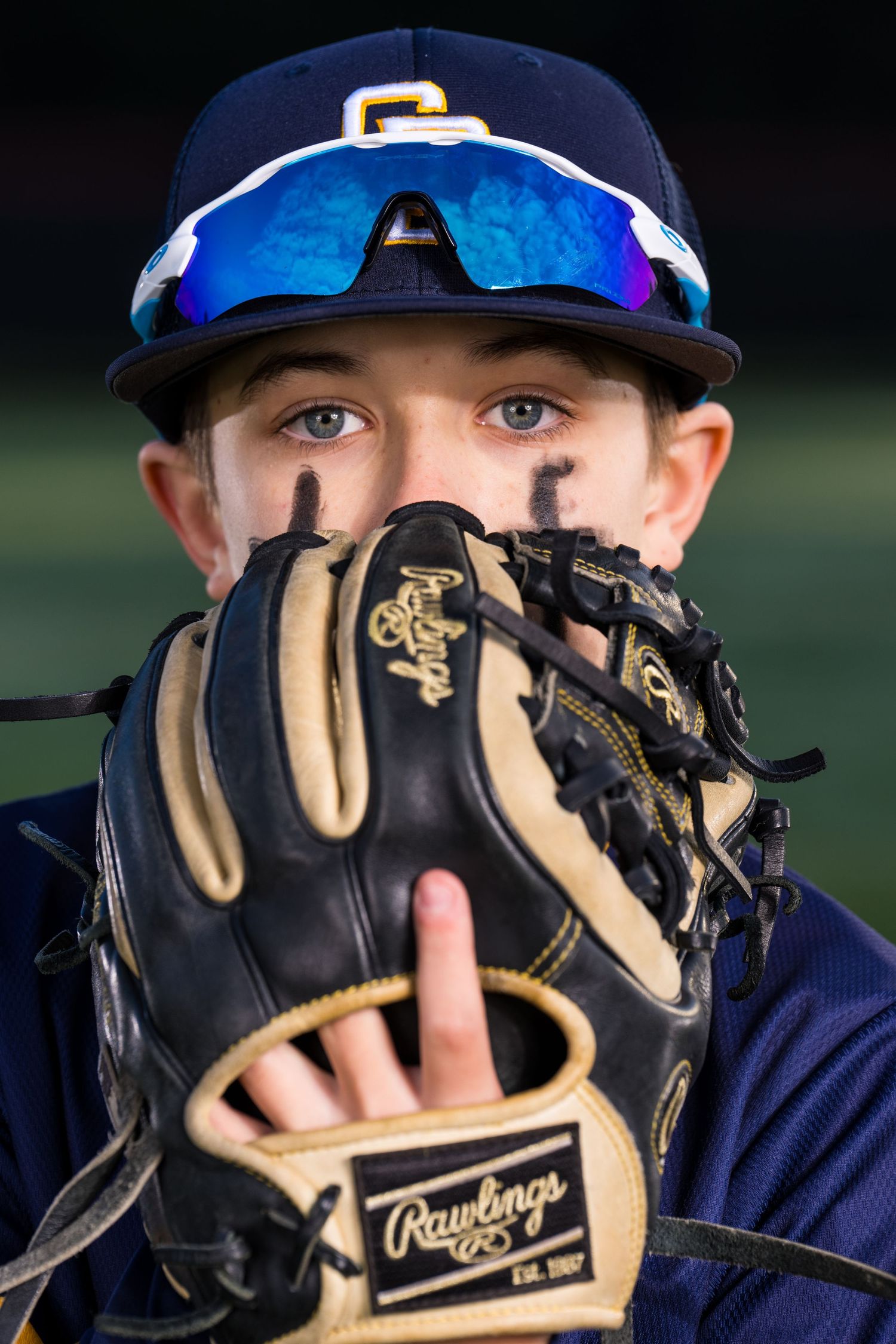 A baseball player from the Stods Dusters baseball team is posing with a baseball mitt partially covering his face.